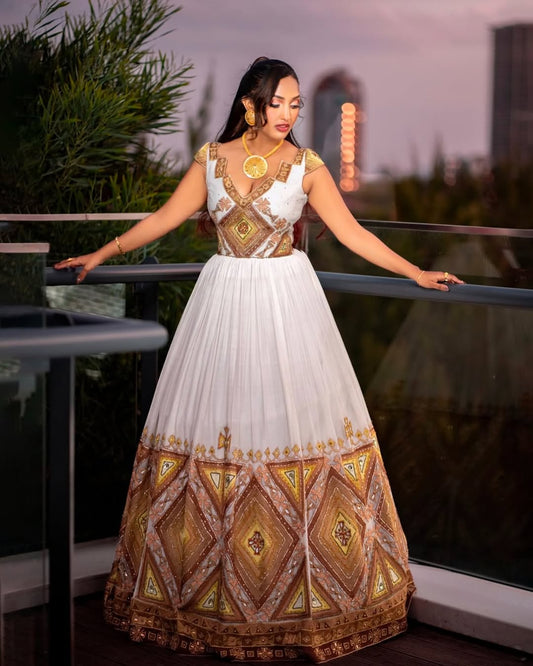 Woman wearing a white and gold embroidered dress on a balcony with a cityscape background