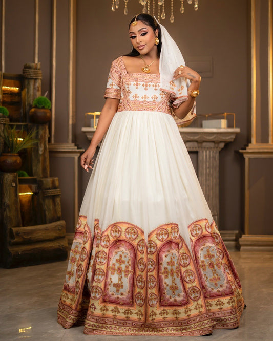 Woman in a traditional outfit with a white and patterned dress in an indoor setting.