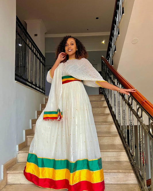 Woman in a white dress with colorful hem standing on a staircase
