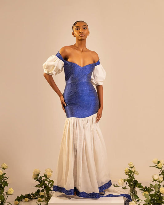 Woman wearing a blue and white dress with puffed sleeves against a beige background