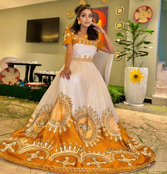 Woman in a traditional outfit with gold and white design in a decorated room.