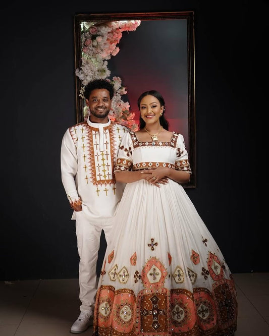 Man and woman in traditional attire standing in front of a floral backdrop