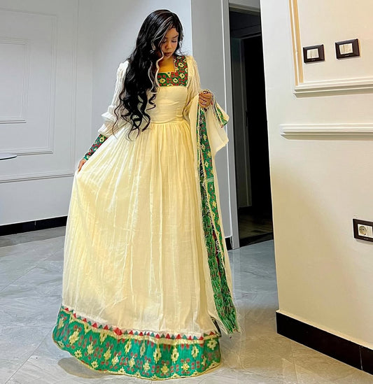 Woman in a traditional outfit with green and red patterns in an indoor setting