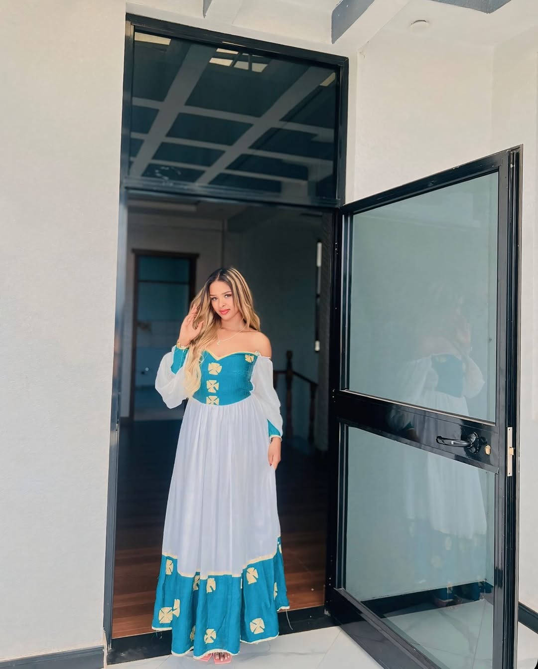 Woman in a blue and white dress standing in a doorway.