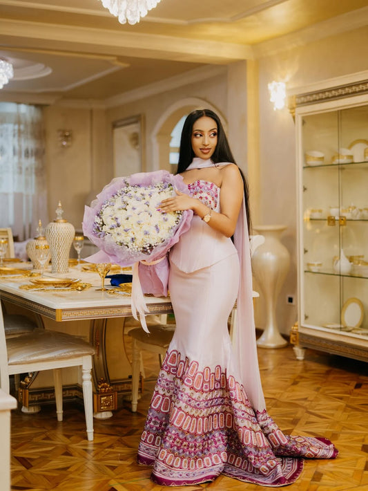 Woman in a pink and purple saree holding flowers in an elegant room.