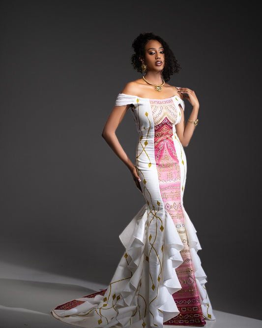 Model wearing a white dress with colorful patterns on a dark background