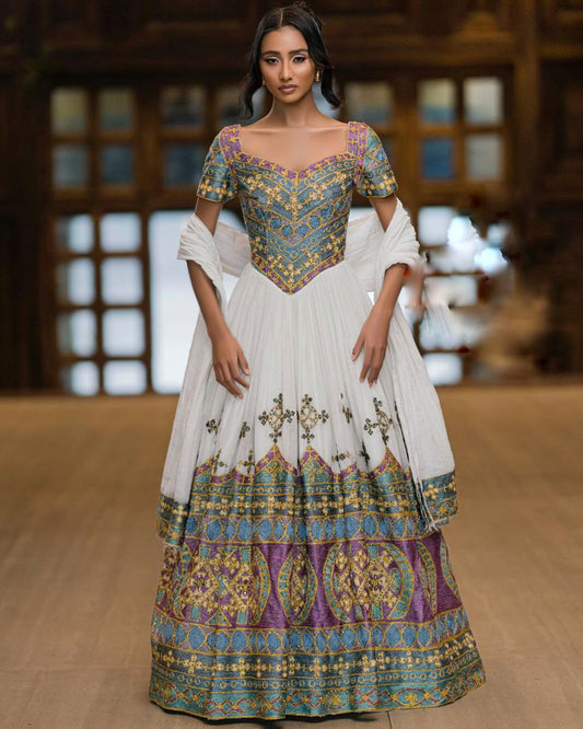 Woman wearing a traditional outfit with intricate patterns in a blurred indoor setting
