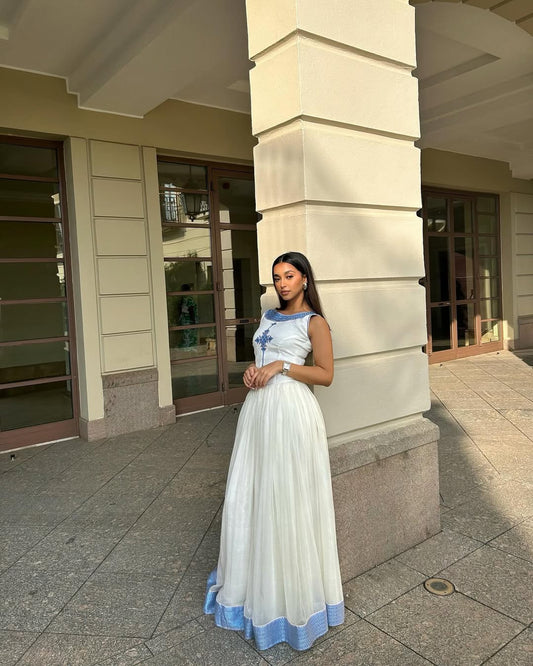 Woman in a white and blue dress standing in front of a building.