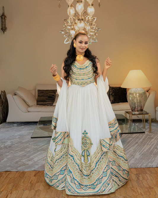Woman in a traditional outfit standing in a decorated room with a chandelier and lamp.