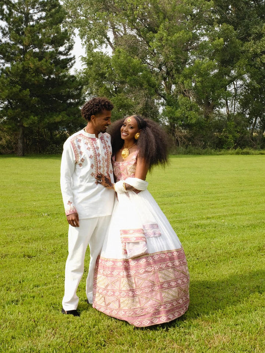 Couple in formal attire standing in a grassy field with trees in the background