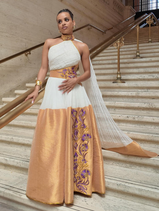 Woman in a white and gold dress with floral patterns on a staircase