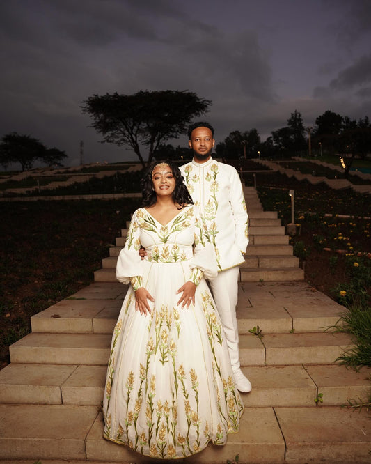 Couple in formal attire standing on stone steps outdoors at dusk.