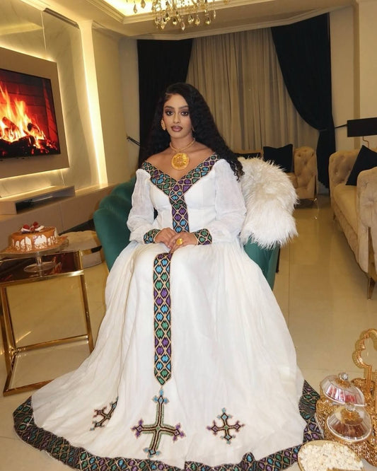Woman in a white dress with intricate patterns in a luxurious room.