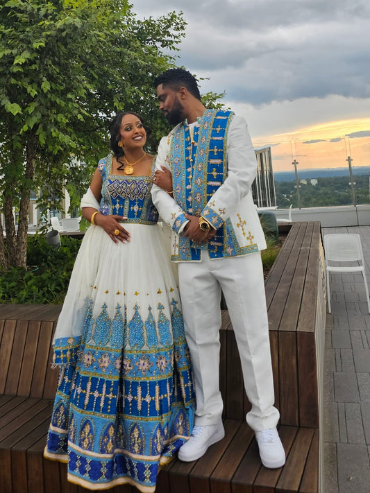 Couple in traditional attire standing on a rooftop with a scenic background