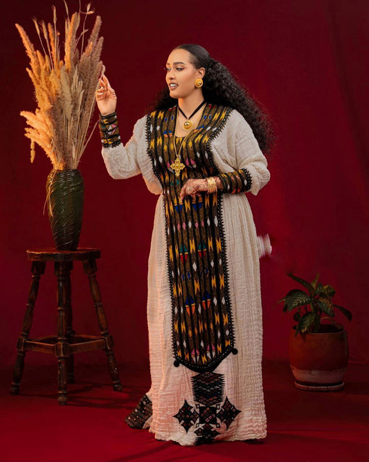 Woman in traditional attire holding a dried plant against a red background