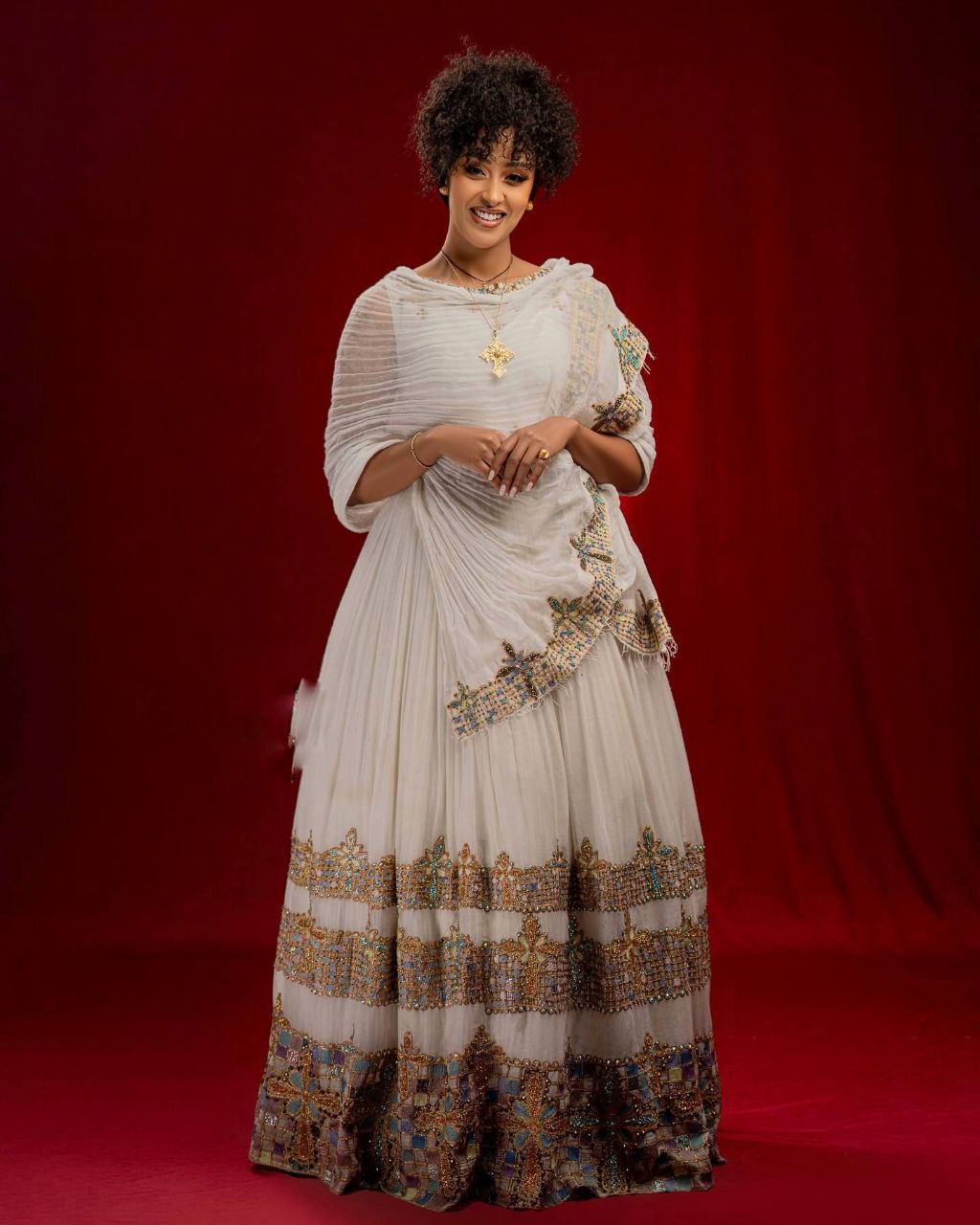 Woman in a traditional outfit with intricate patterns on a red background