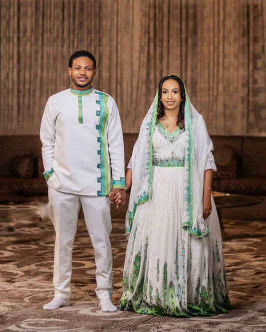 Man and woman in traditional attire standing together indoors.