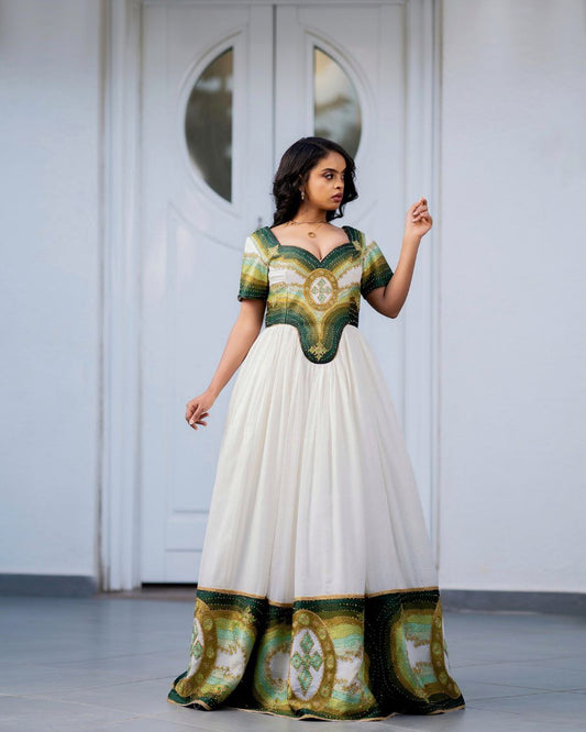 Woman wearing a green and white patterned dress in front of a white door.